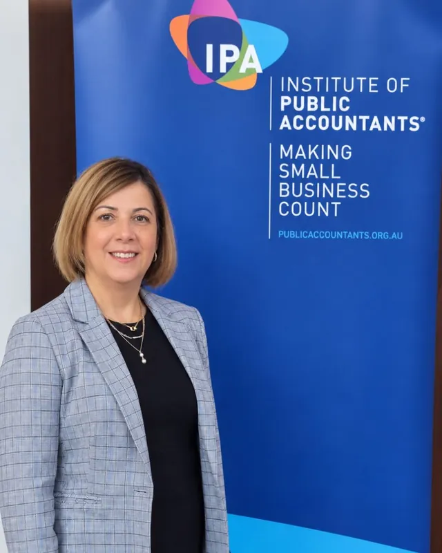 Marion Dellepiane in front of the Institute of Public Accountants banner